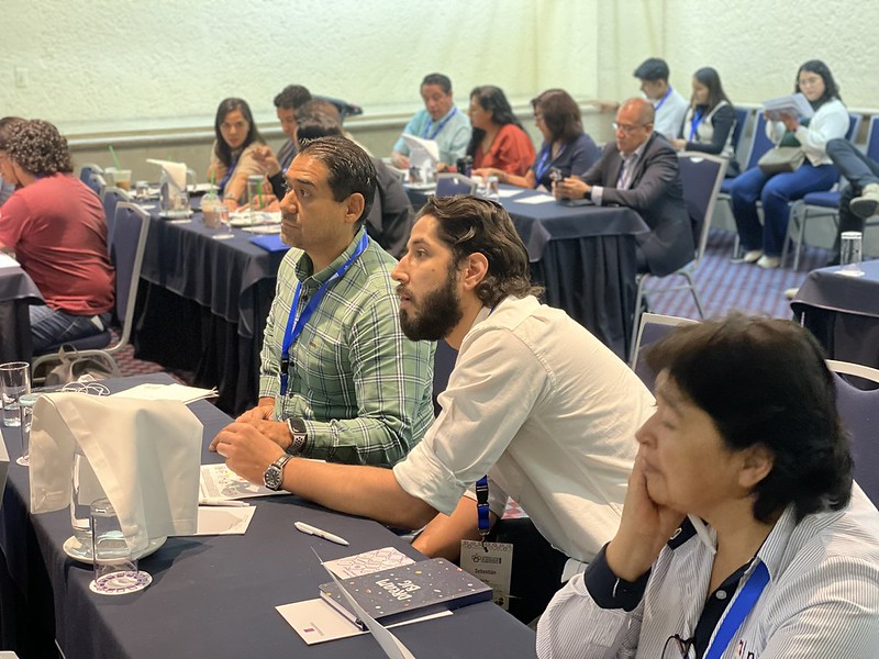 Asistentes del Congreso Latam 2025 sentados en mesas durante una conferencia en la Ciudad de México