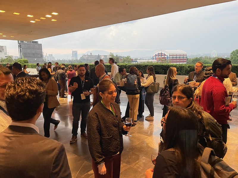 Grupo de asistentes disfrutando de un networking en la terraza con vista al atardecer de la Ciudad de México