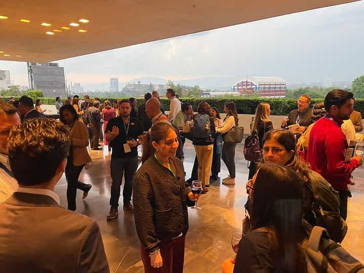 Grupo de asistentes disfrutando de un networking en la terraza con vista al atardecer de la Ciudad de México