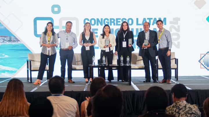 Grupo de ponentes y homenajeados con sus reconocimientos en el escenario del Congreso Latam 2024