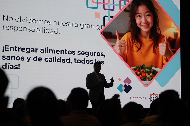 Ponente del Congreso 2025 en silueta frente a la pantalla con un mensaje sobre la responsabilidad de entregar alimentos seguros