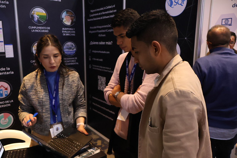 Representante de un expositor mostrando una solución tecnológica a asistentes del Congreso Colombia 2024